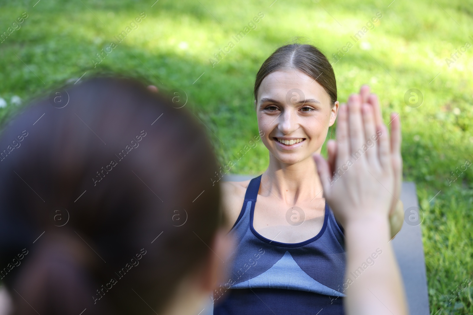 Photo of Young woman with professional personal trainer giving high five outdoors