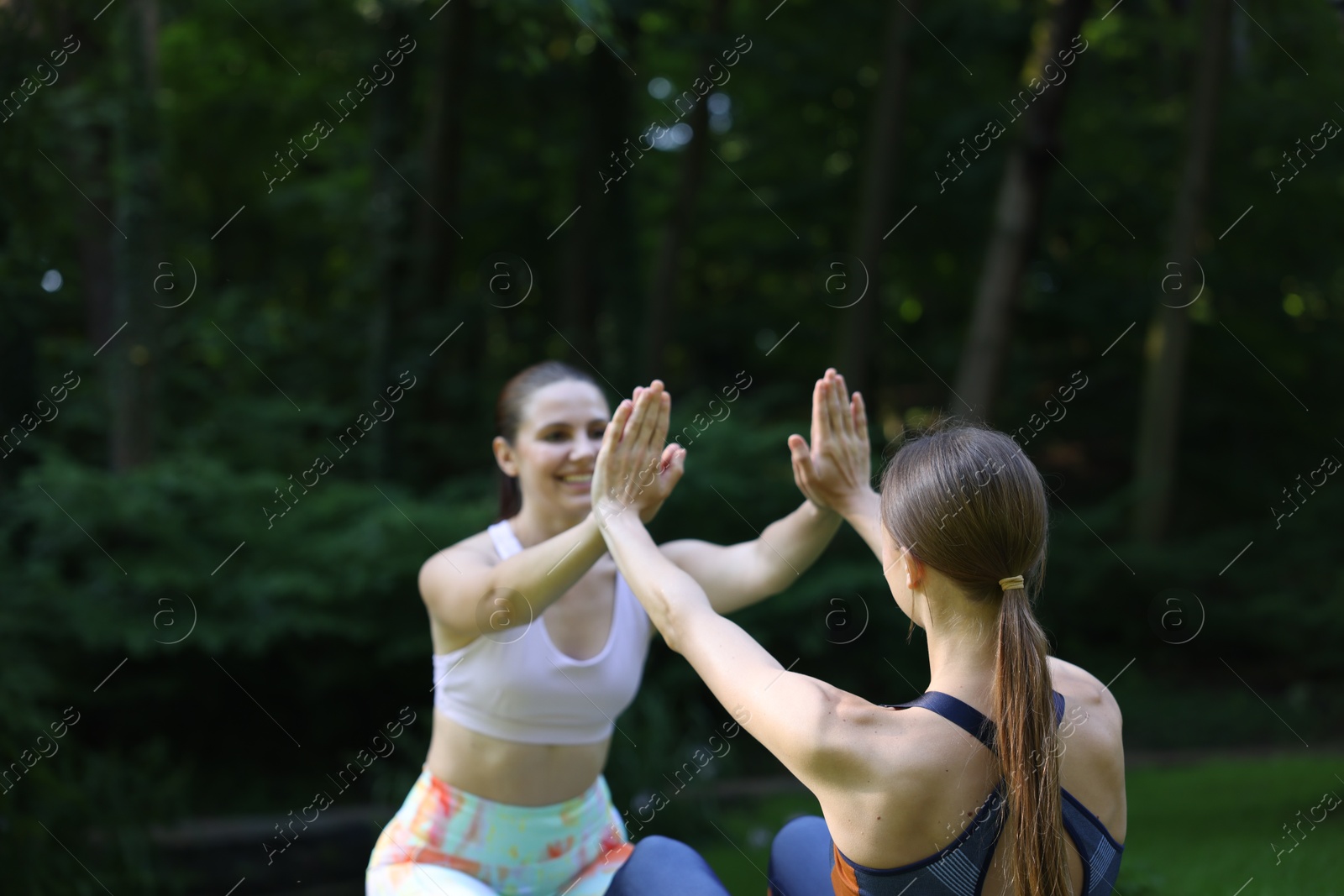 Photo of Young woman with professional personal trainer giving high five outdoors
