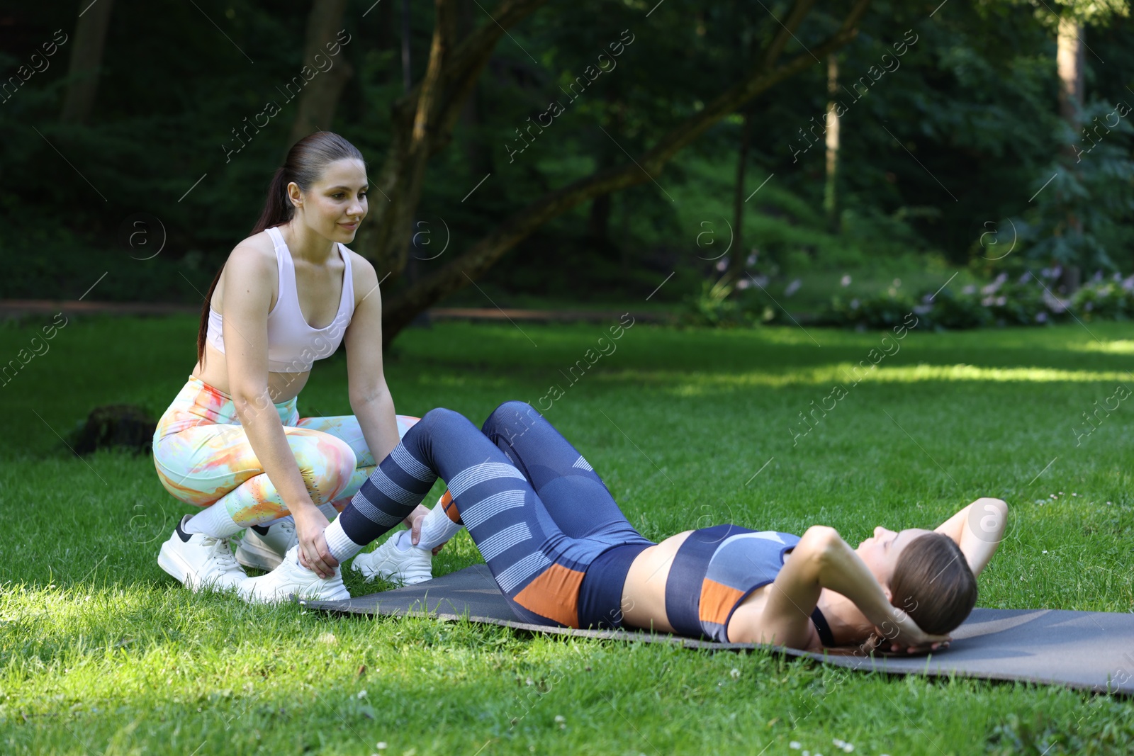 Photo of Young woman exercising with professional personal trainer outdoors