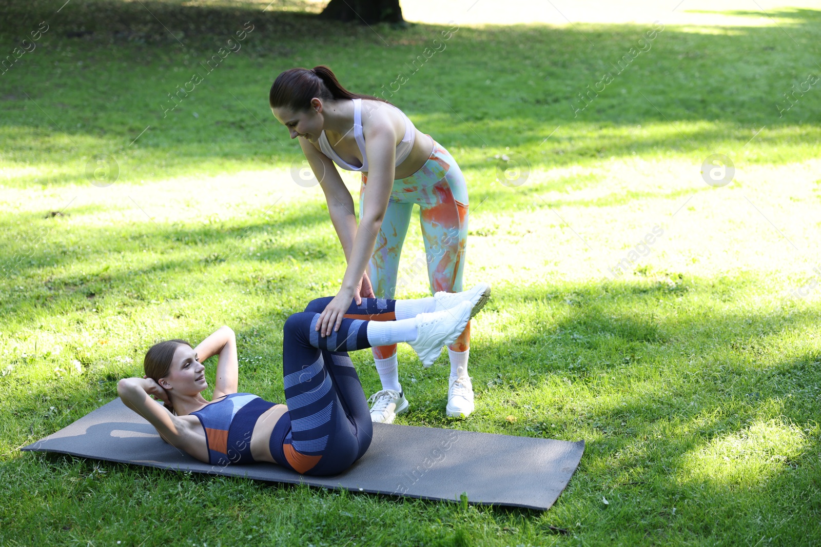 Photo of Young woman exercising with professional personal trainer outdoors. Space for text