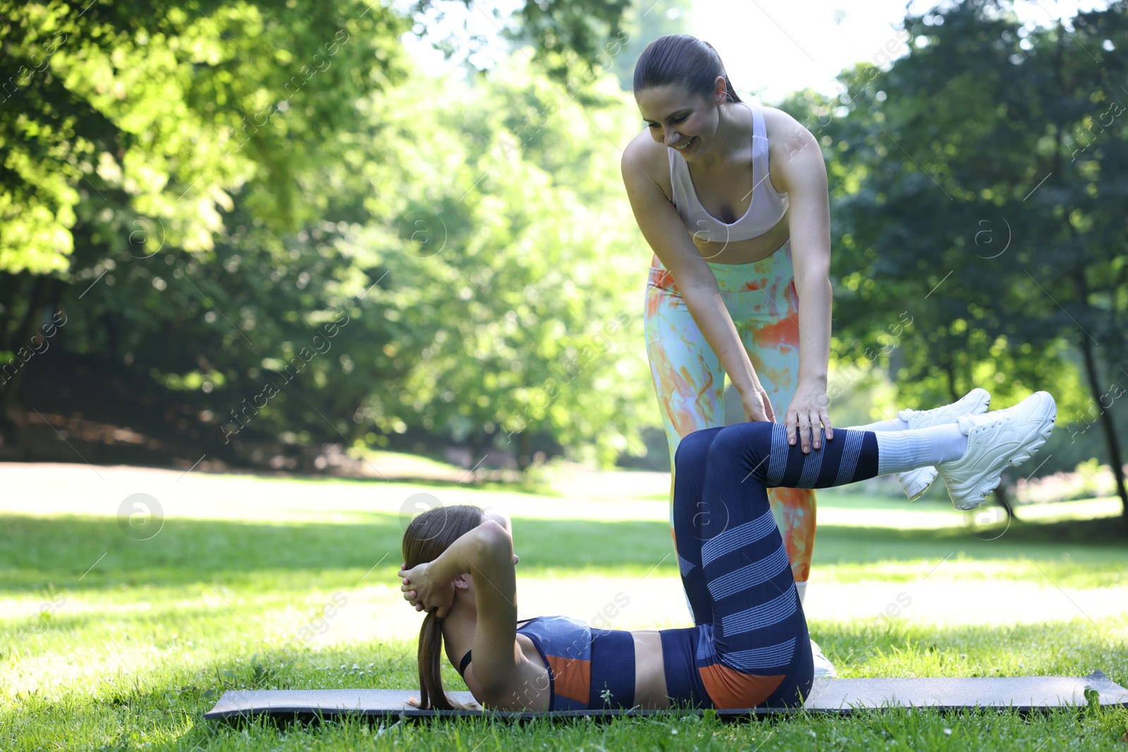 Photo of Young woman exercising with professional personal trainer outdoors. Space for text