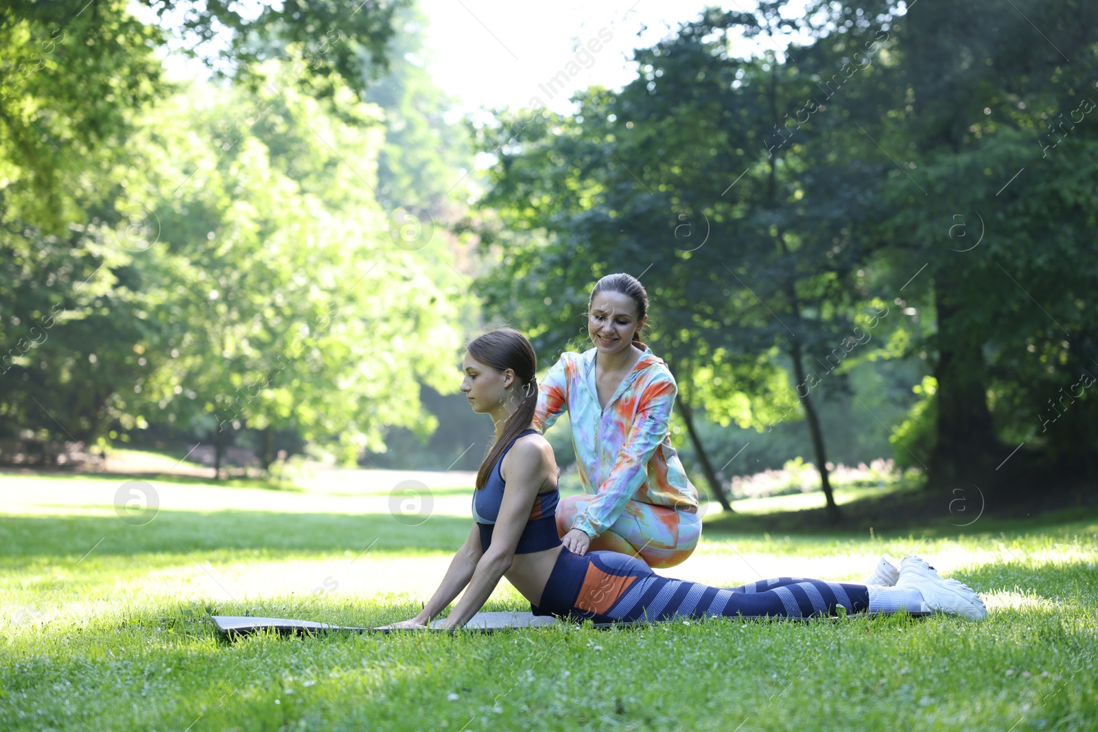 Photo of Young woman exercising with professional personal trainer outdoors