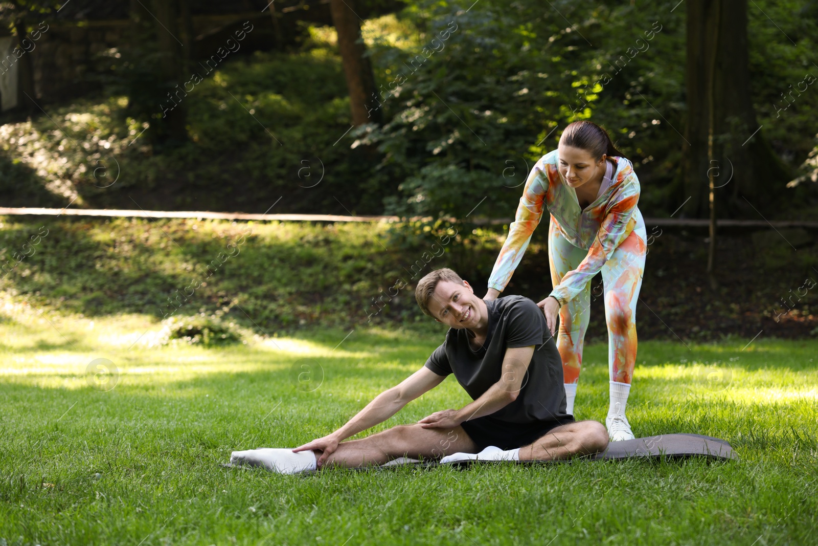Photo of Young man exercising with professional personal trainer outdoors. Space for text