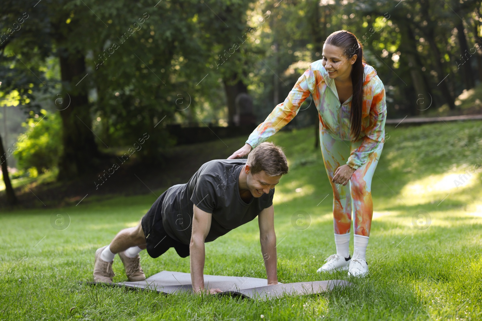 Photo of Young man exercising with professional personal trainer outdoors