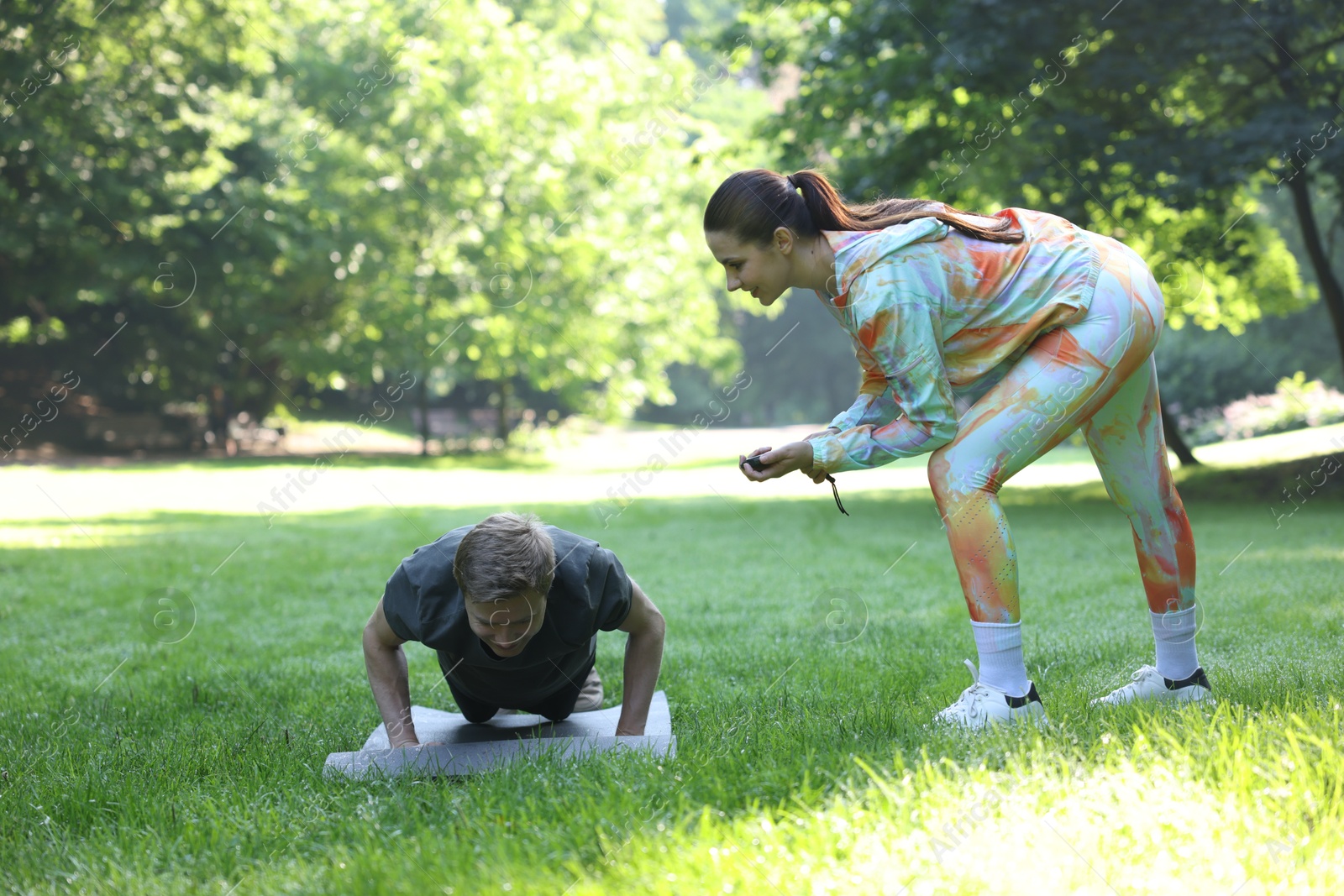 Photo of Young man exercising with professional personal trainer outdoors