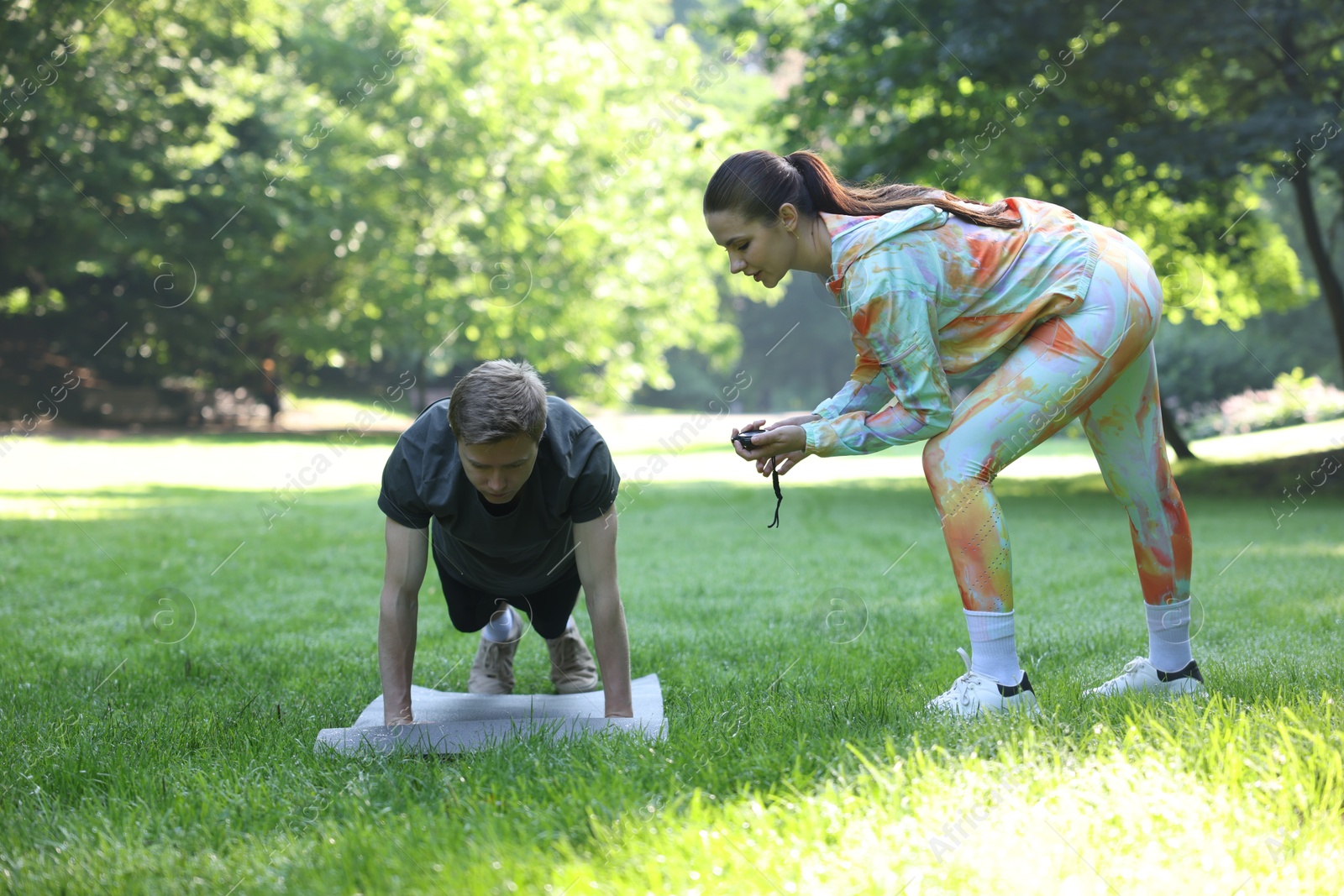 Photo of Young man exercising with professional personal trainer outdoors