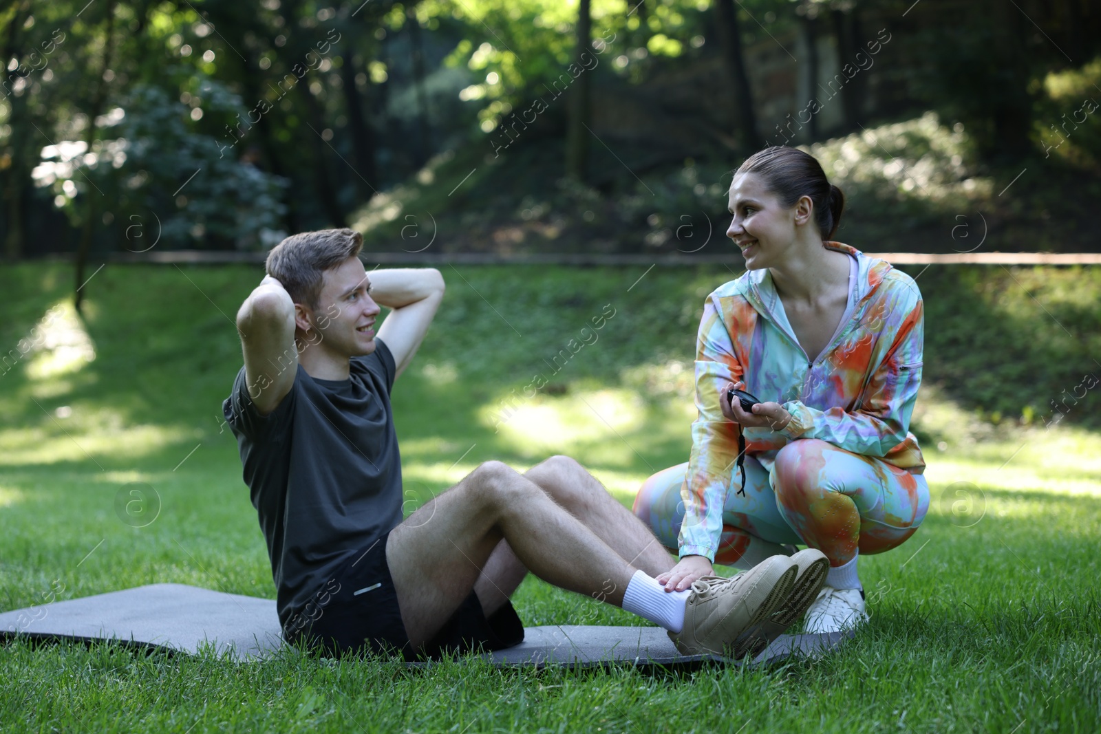 Photo of Young man exercising with professional personal trainer outdoors