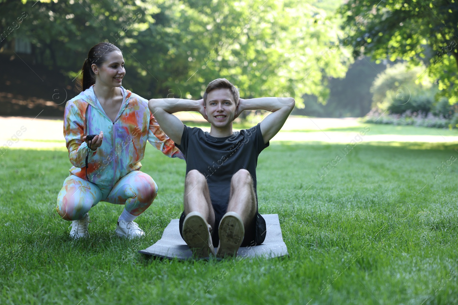 Photo of Young man exercising with professional personal trainer outdoors. Space for text