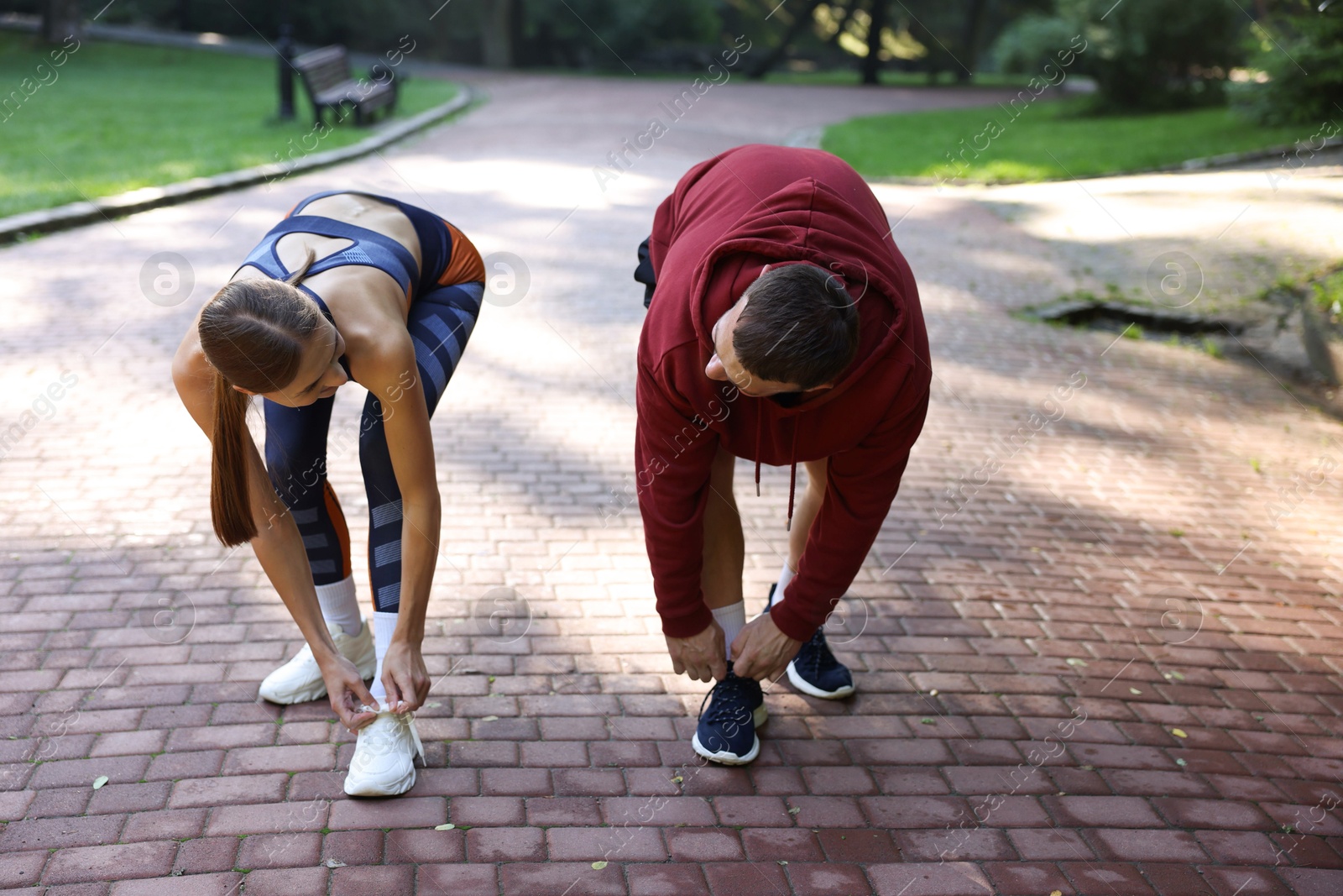 Photo of Young woman and professional personal trainer tying shoes outdoors