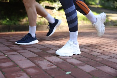 Photo of Young woman running with professional personal trainer outdoors, closeup