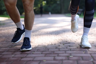 Photo of Young woman running with professional personal trainer outdoors, closeup