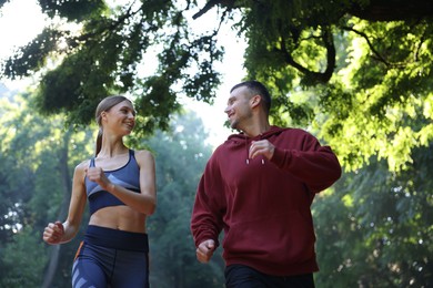 Photo of Young woman running with professional personal trainer outdoors, low angle view