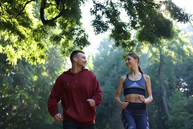 Photo of Young woman running with professional personal trainer outdoors, low angle view