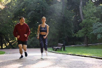 Photo of Young woman running with professional personal trainer outdoors. Space for text