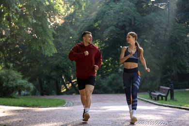Photo of Young woman running with professional personal trainer outdoors