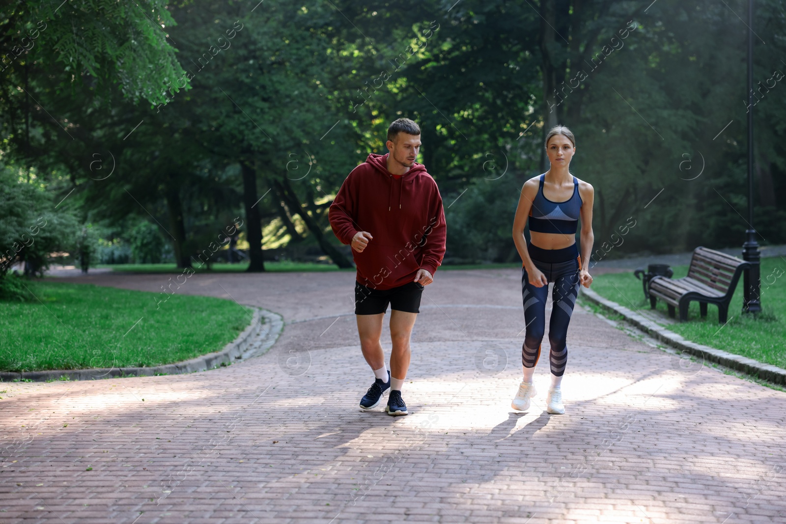 Photo of Young woman running with professional personal trainer outdoors. Space for text