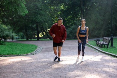 Photo of Young woman running with professional personal trainer outdoors. Space for text