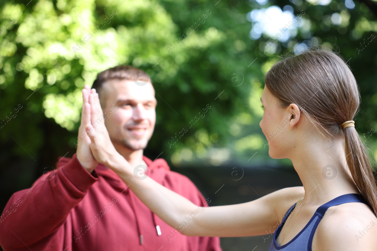 Young woman with professional personal trainer giving high five outdoors, selective focus Photo of Young woman with professional personal trainer giving high five outdoors, selective focus