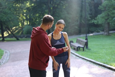 Photo of Young woman exercising with professional personal trainer outdoors