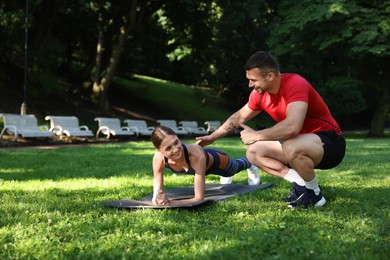 Photo of Young woman exercising with professional personal trainer outdoors. Space for text