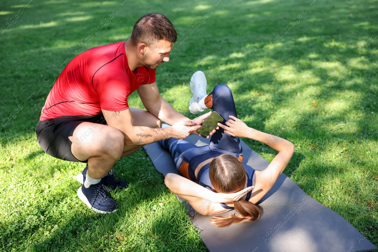 Photo of Young woman exercising with professional personal trainer outdoors