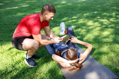 Photo of Young woman exercising with professional personal trainer outdoors
