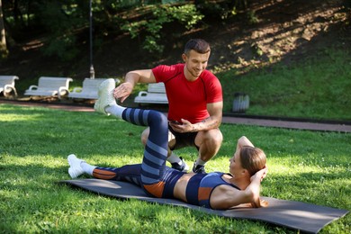 Photo of Young woman exercising with professional personal trainer outdoors