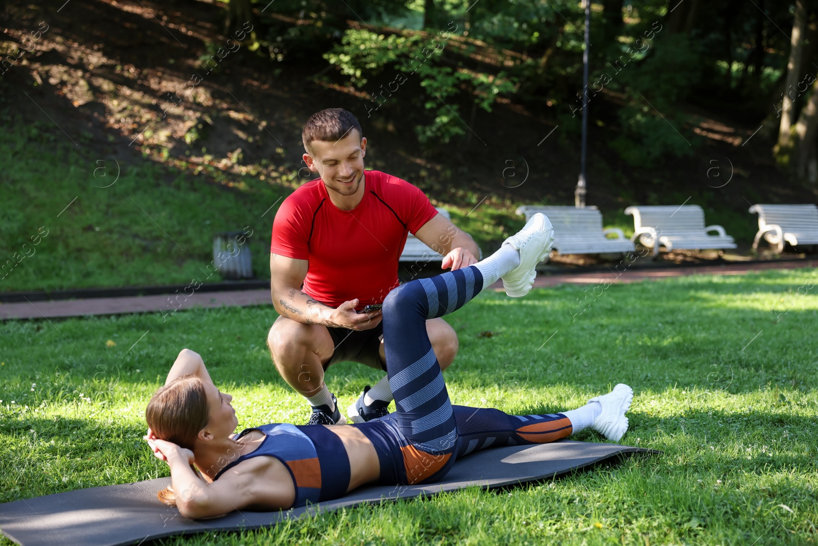 Young woman exercising with professional personal trainer outdoors Photo of Young woman exercising with professional personal trainer outdoors