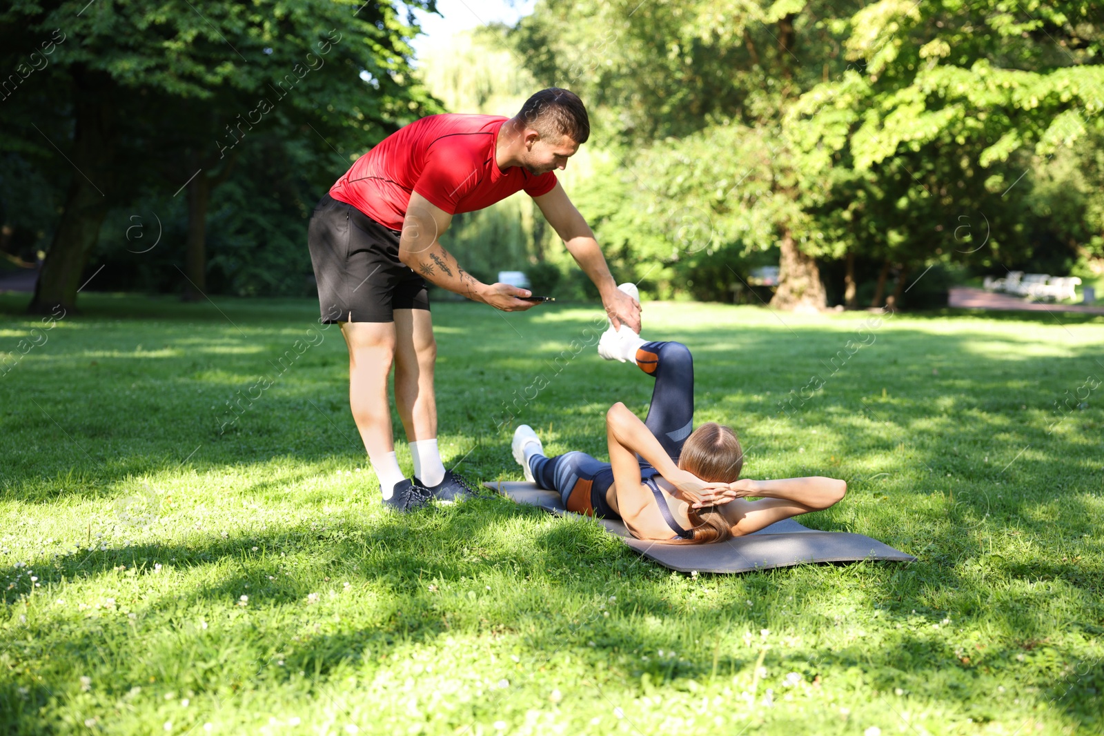 Photo of Young woman exercising with professional personal trainer outdoors