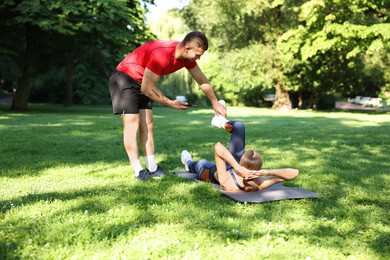 Photo of Young woman exercising with professional personal trainer outdoors