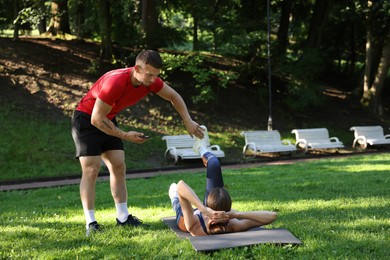 Photo of Young woman exercising with professional personal trainer outdoors. Space for text