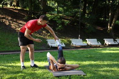 Photo of Young woman exercising with professional personal trainer outdoors. Space for text