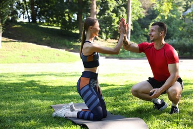 Photo of Young woman exercising with professional personal trainer outdoors