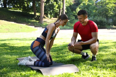 Photo of Young woman exercising with professional personal trainer outdoors