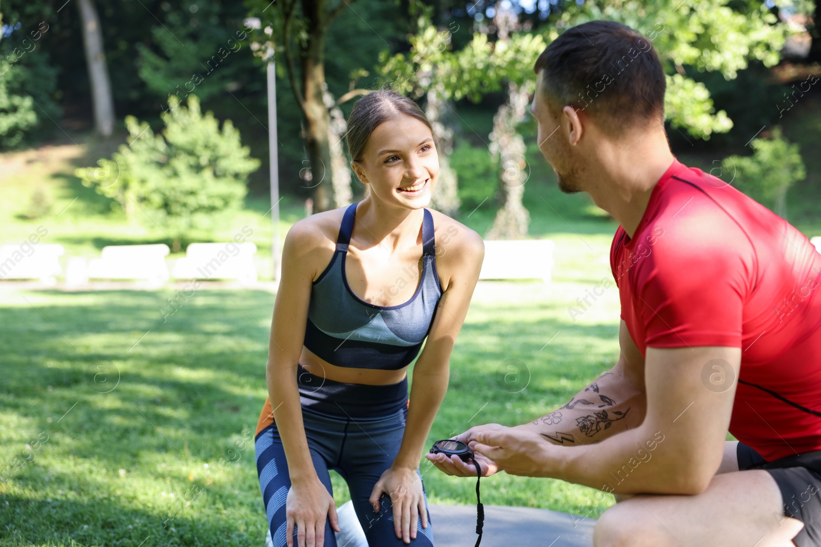 Photo of Young woman exercising with professional personal trainer outdoors