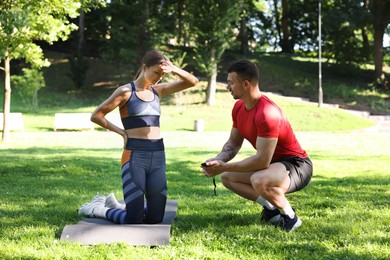 Photo of Young woman exercising with professional personal trainer outdoors