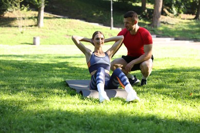 Photo of Young woman exercising with professional personal trainer outdoors. Space for text