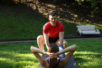 Photo of Young woman exercising with professional personal trainer outdoors