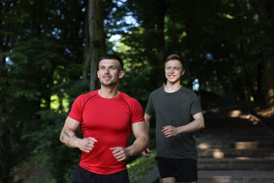 Photo of Young man running with professional personal trainer outdoors