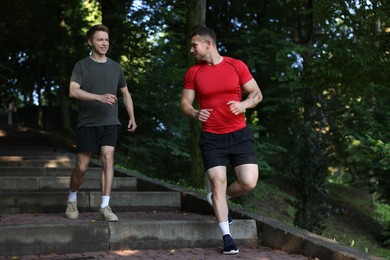 Photo of Young man running down on stairs with professional personal trainer outdoors