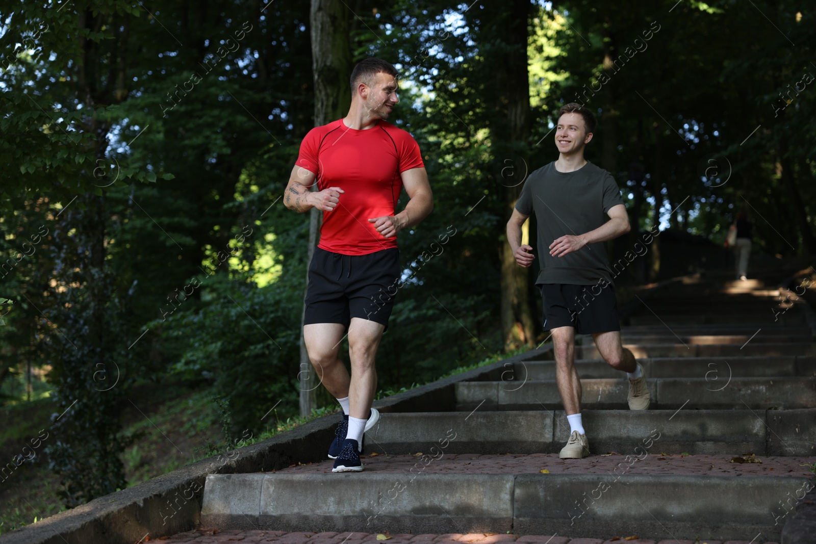 Young man running down on stairs with professional personal trainer outdoors Photo of Young man running down on stairs with professional personal trainer outdoors