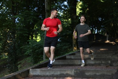 Photo of Young man running down on stairs with professional personal trainer outdoors