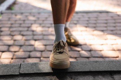 Photo of Young man with stylish shoes before running outdoors, closeup
