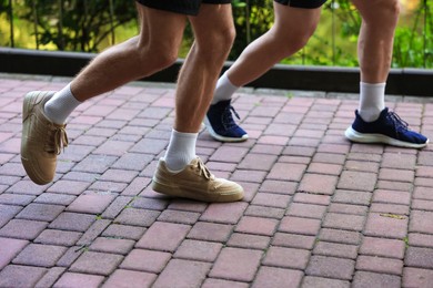 Photo of Young man running with professional personal trainer outdoors, closeup