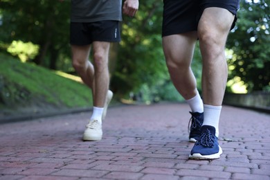 Photo of Young man running with professional personal trainer outdoors, closeup