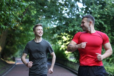 Photo of Young man running with professional personal trainer outdoors