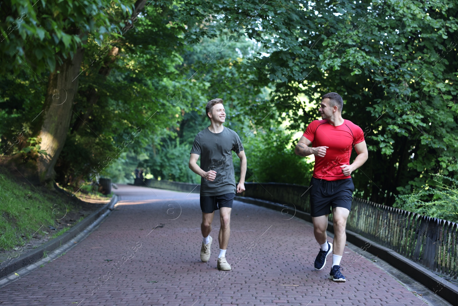 Young man running with professional personal trainer outdoors. Space for text Photo of Young man running with professional personal trainer outdoors. Space for text