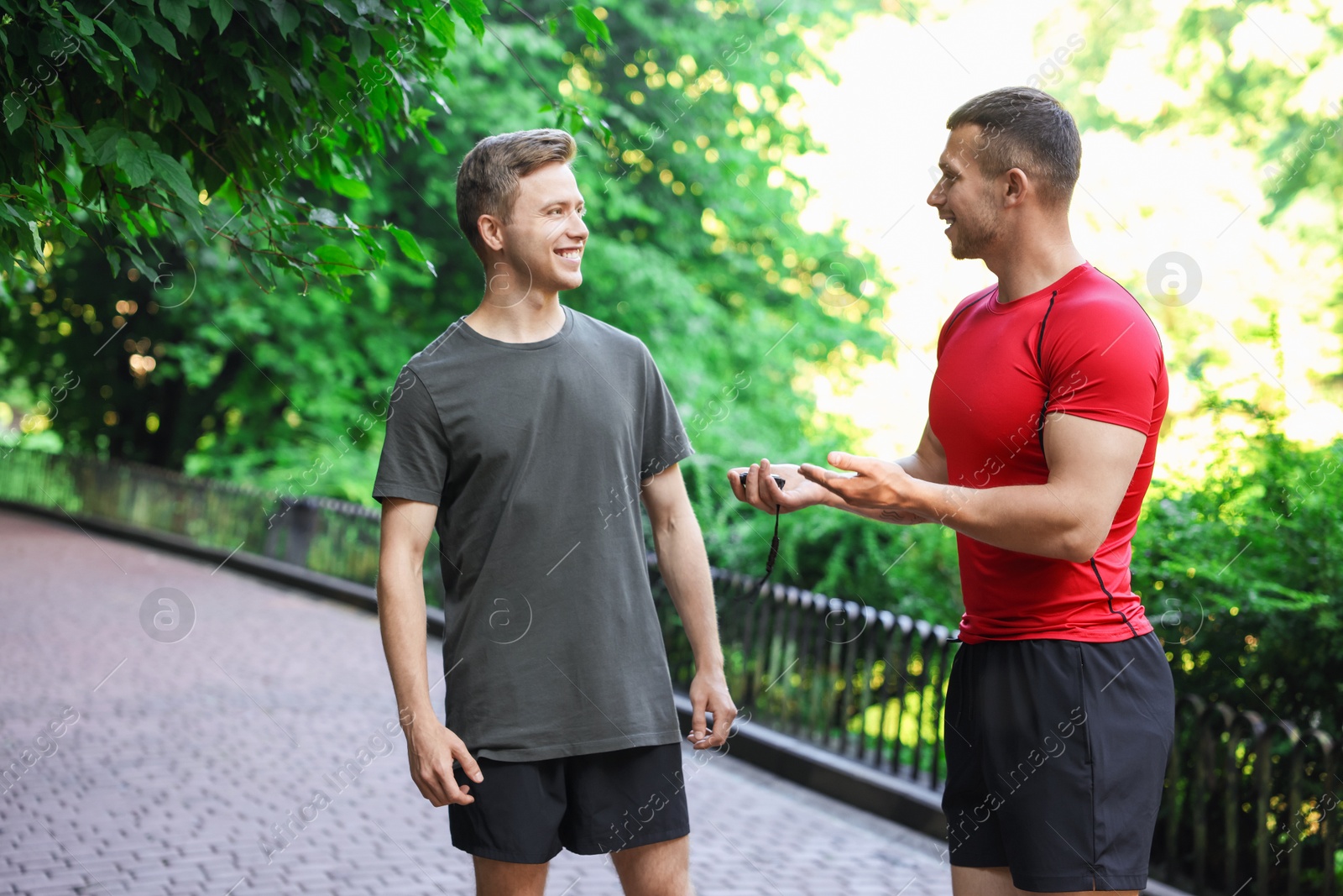 Photo of Young man with professional personal trainer outdoors