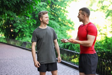 Photo of Young man with professional personal trainer outdoors