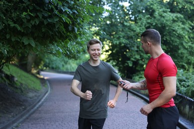 Photo of Young man exercising with professional personal trainer outdoors. Space for text